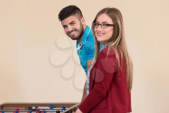 Group Of Young Men And Women Enjoying A Game Of Foosball