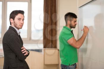 Young Arabic Student Writes Some Answer on The Whiteboard And The Teacher Observes Him