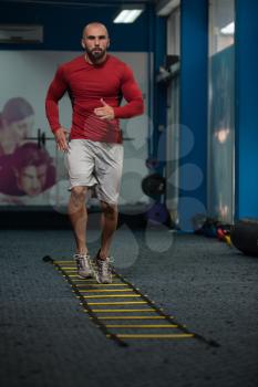 Handsome Man Running On Step Ladders Lying On Floor - Sports And Fitness - Concept Of Healthy Lifestyle - Fitness Male