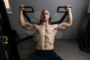 Young Bodybuilder Doing Heavy Weight Exercise For Shoulders On Machine