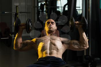 Muscular Man Doing Exercise For Chest With Dumbbells In A Gym
