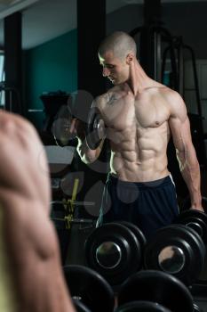 Young Man Working Out Biceps In Front Of A Mirror - Dumbbell Concentration Curls