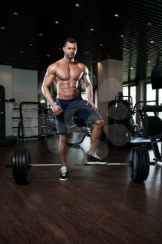 Muscular Man Doing Heavy Weight Exercise For Back With Barbell In Modern Gym