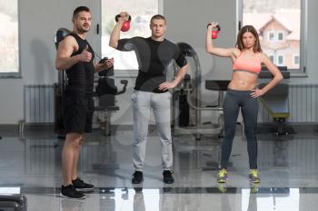 Young Woman And Men Doing Exercise With Kettle Bell In The Gym