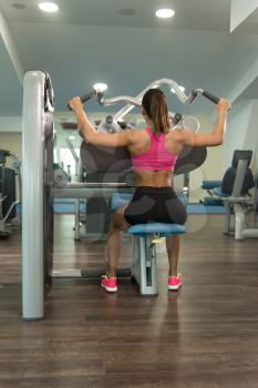 Young Fitness Woman Working Out Back On Machine In Fitness Center