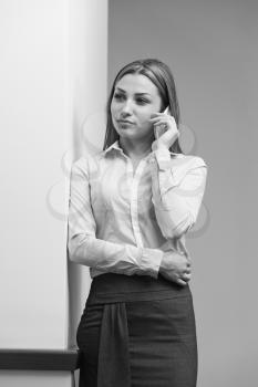 Indoor Portrait Of A Beautiful Happy Brunette Woman Or Businesswoman Talking On Her Cell Phone - City Business Wwoman Working