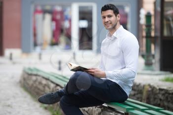 Adult Muslim Man Is Reading The Koran Outdoors