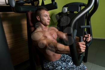 Muscular Athletic Bodybuilder Fitness Model Doing Heavy Weight Exercise For Chest On Machine