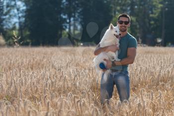 Young Man Standing With Dog German Spitz In Harvested Field