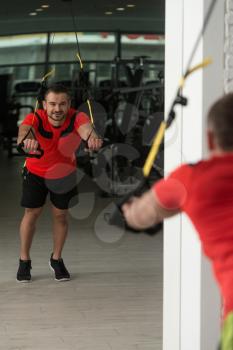 Personal Trainer Does Crossfit With Trx Fitness Straps In The Gym's Studio