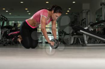 Attractive Woman Exercising With Wheel Roller For Abs On Floor In Gym As Part Of Fitness Training