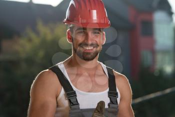 Portrait Of A Construction Worker With Red Helmet Making Thumbs Up Sign