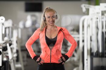 Healthy Young Woman Listening Music From His Mp3 Player In Modern Fitness Center Gym