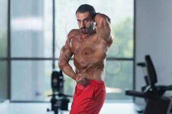 Portrait Of A Young Physically Fit Latin Man Performing Side Chest Pose - Muscular Athletic Bodybuilder Fitness Model Posing After Exercises