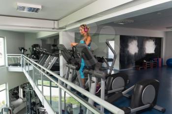Attractive Mature Woman Doing Aerobics Elliptical Walker In Modern Fitness Center