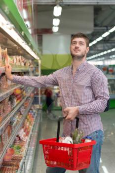Handsome Young Man Shopping For Meat And Fish In Produce Department Of A Grocery Store - Supermarket - Shallow Deep Of Field