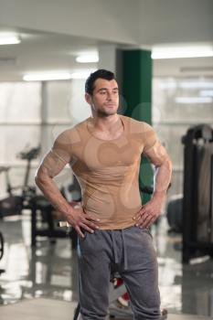 Healthy Young Man in Brown T-shirt Standing Strong and Flexing Muscles - Muscular Athletic Bodybuilder Fitness Model Posing After Exercises
