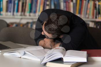 Sleeping Caucasian Student Sitting And Leaning On Pile Of Books In College - Shallow Depth Of Field