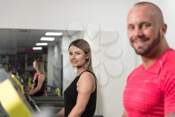 Personal Trainer Showing Young Woman How To Train On Treadmill In The Gym