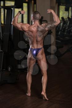Healthy Young Tattoo Man Standing Strong In The Gym And Flexing Muscles - Muscular Athletic Bodybuilder Fitness Model Posing After Exercises