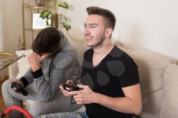 Two Men Competitive Friends Playing Video Games and Excited Happy Cheerful at Home