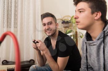 Two Brothers or Friends Playing Video Games Together as They Relax on a Couch in the Living Room