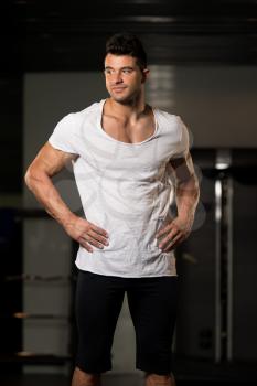 Healthy Young Man in White T-shirt Standing Strong and Flexing Muscles - Muscular Athletic Bodybuilder Fitness Model Posing After Exercises