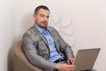 Confident Businessman at Home He Is Having a Coffee Break in the Living Room and Networking With His Laptop