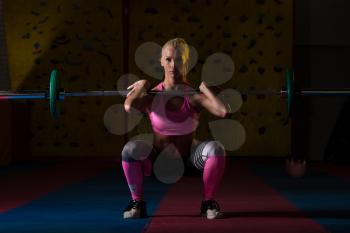 Young Woman Performing Barbell Squats - One Of The Best Bodybuilding Exercise For Legs