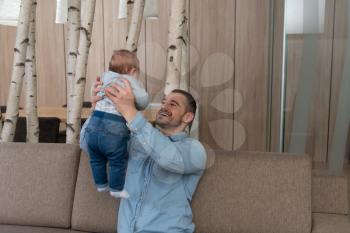 Father Playing With His Cute Baby on the Couch at Home