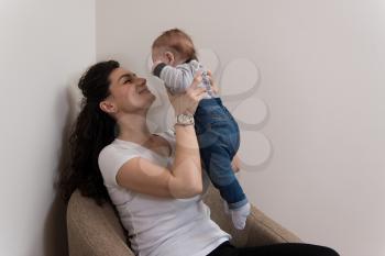 Happy Mother with Child Baby Boy at Home in the Living Room Playing and Laughing