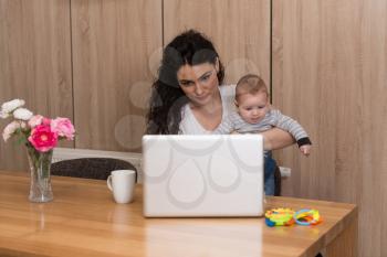 Relaxed Young Woman With Cute Little Baby and Using Laptop Computer