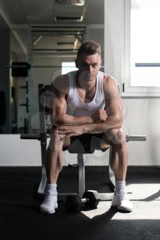 Attractive Man Resting On Bench After Exercise In Fitness Center