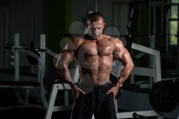 Healthy Mature Man Standing Strong In The Gym And Flexing Muscles - Muscular Athletic Bodybuilder Fitness Male Posing After Exercises