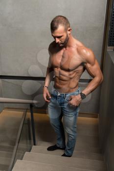 Healthy Young Man Standing Strong Standing On Stairs and Flexing Muscles - Muscular Athletic Bodybuilder Fitness Model Posing After Exercises - a Place for Your Text