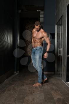 Healthy Young Man Standing Strong Standing On Corridor and Flexing Muscles - Muscular Athletic Bodybuilder Fitness Model Posing After Exercises - a Place for Your Text