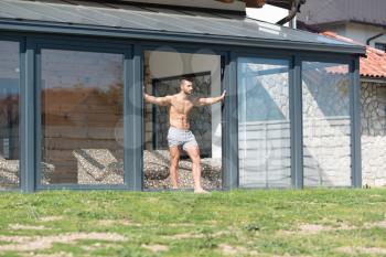 Serious Man Standing And Flexing Muscles At Sunny Day