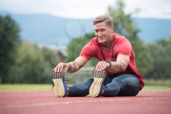 Portrait of Fit and Sporty Young Man Doing Stretching in the Park