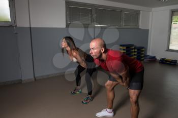 Young Woman And Man Doing Exercise With Kettle Bell In The Gym