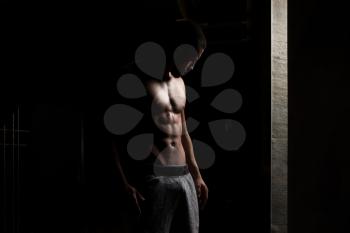 Portrait Of A Physically Fit Man Showing His Well Trained Body In Dark Room