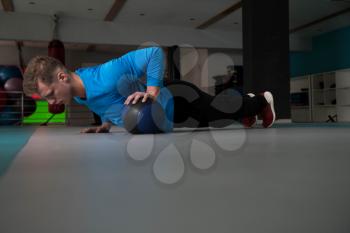 Handsome Young Man Doing Pushups With Medicine Ball As Part Of Bodybuilding Training
