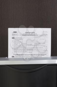 Foreign Earned Income form in shredder with wooden desk in background