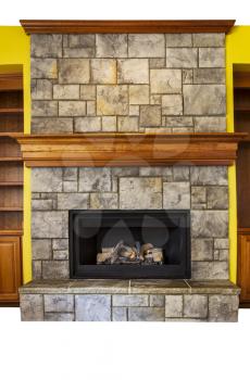 Full Vertical shot of gas insert fireplace with yellow accents walls and oak wooden shelves