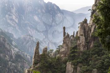 Large Vertical rocks in China's Yellow Mountains with misty sky in background 