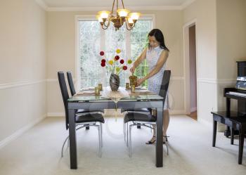 photo of mature woman pouring tea into cup while in family formal dining room with daylight coming through large windows in background