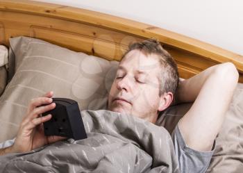 Mature man checking time for wake up in the morning