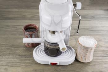Espresso maker with drip black coffee and whipped latte coffee on wooden table