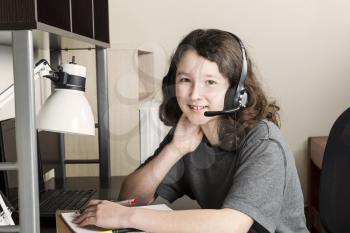 Young girl doing homework with headset on while sitting at her desk