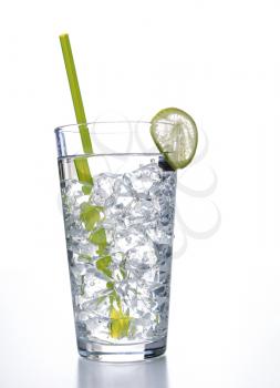 Vertical photo of a tall glass of water with ice cubes, slice of lime and a green straw on a white background