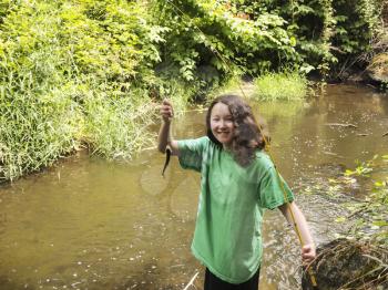 Photo of young girl holding up small trout while fishing on a small stream 
